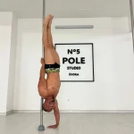 Praticante em posição invertida na barra, com uma mão apoiada no chão